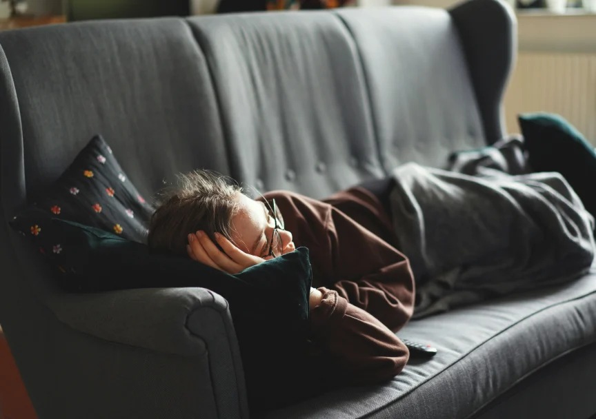 Person sitting quietly on a couch while struggling to relax and rest